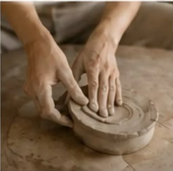 Hands shaping a piece of clay on a work table